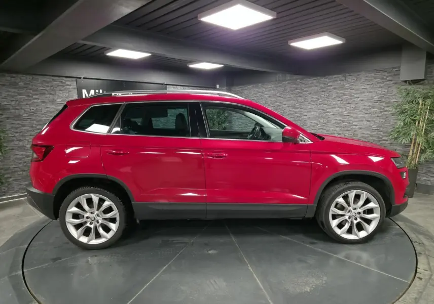 Profil droit d'un SKODA KAROQ rouge 2018 avec jantes alliage 19 pouces et arches de roues en plastique noir.