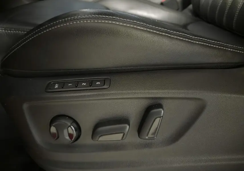 Gros plan sur les commandes de réglage électrique du siège conducteur en cuir noir du Skoda Karoq rouge.