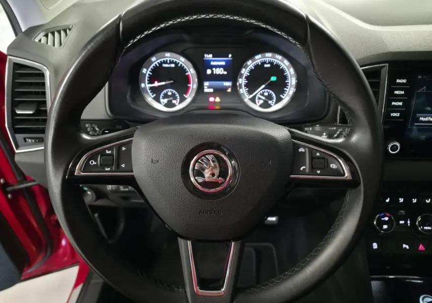 Vue rapprochée du volant cuir noir avec logo SKODA et tableau de bord numérique du Karoq rouge 2018.