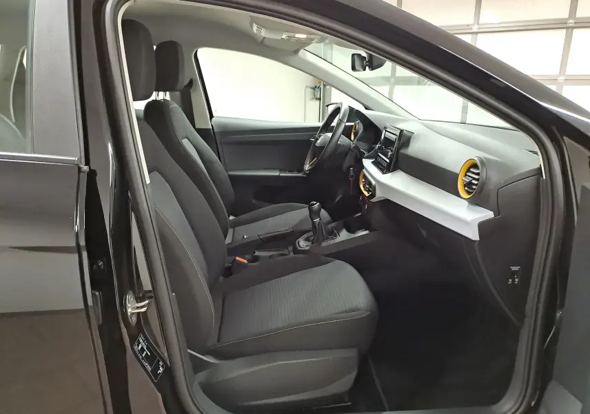 Intérieur avant droit d'une SEAT IBIZA 2024 noir minuit, montrant sièges tissu noirs et tableau de bord avec aérateurs jaunes.