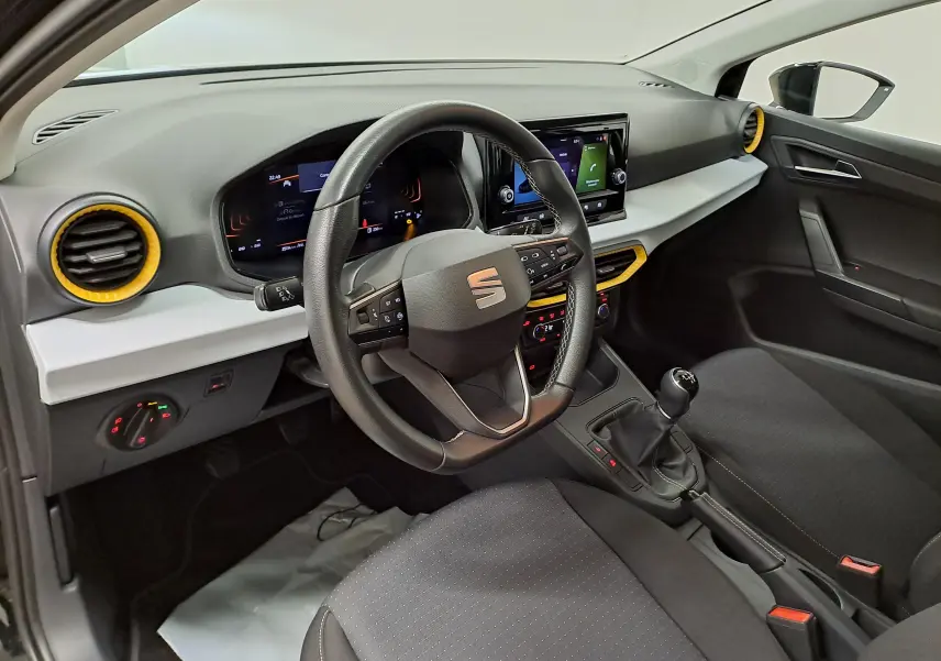 Vue intérieure côté conducteur de la SEAT Ibiza 2024 noir minuit, avec volant multifonction et détails jaunes autour des aérateurs.