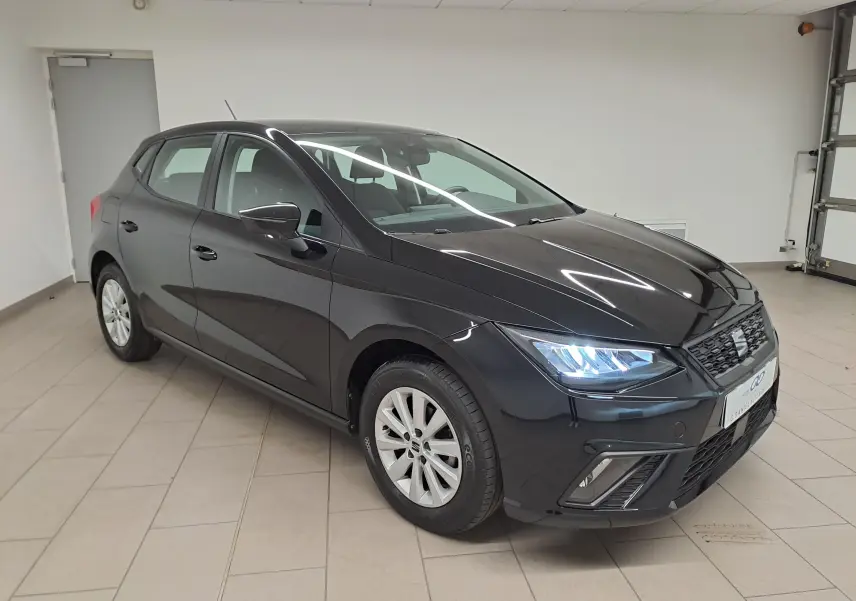 SEAT Ibiza 2024 noir minuit vue 3/4 avant droit avec phares allumés dans un garage intérieur.
