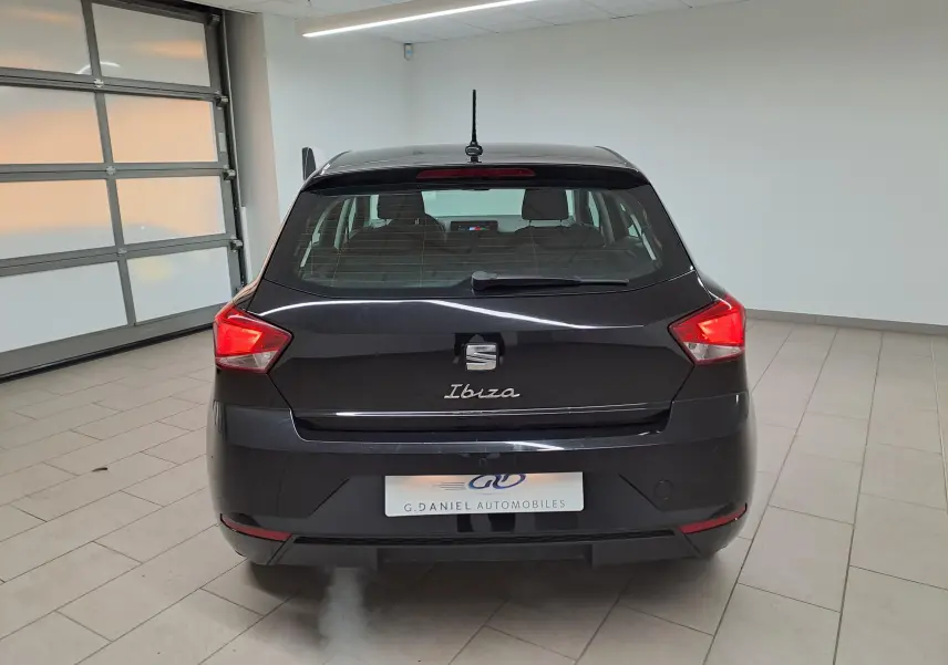 Vue arrière d'une SEAT Ibiza 2024 noir minuit, avec feux rouges allumés dans un garage lumineux.