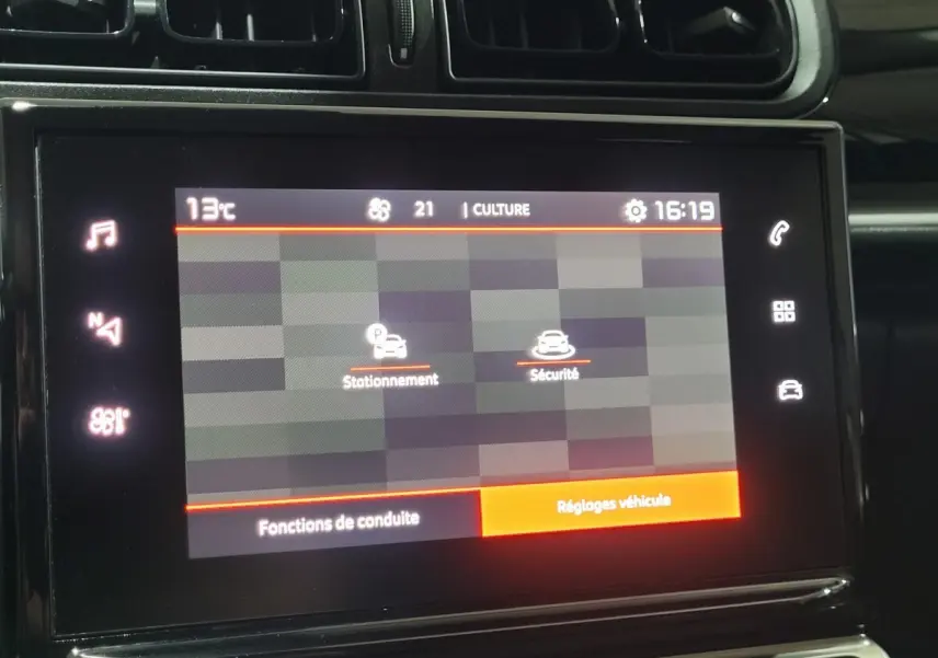 Gros plan sur l'écran tactile central de la Citroën C3 beige, affichant les options de stationnement et sécurité.