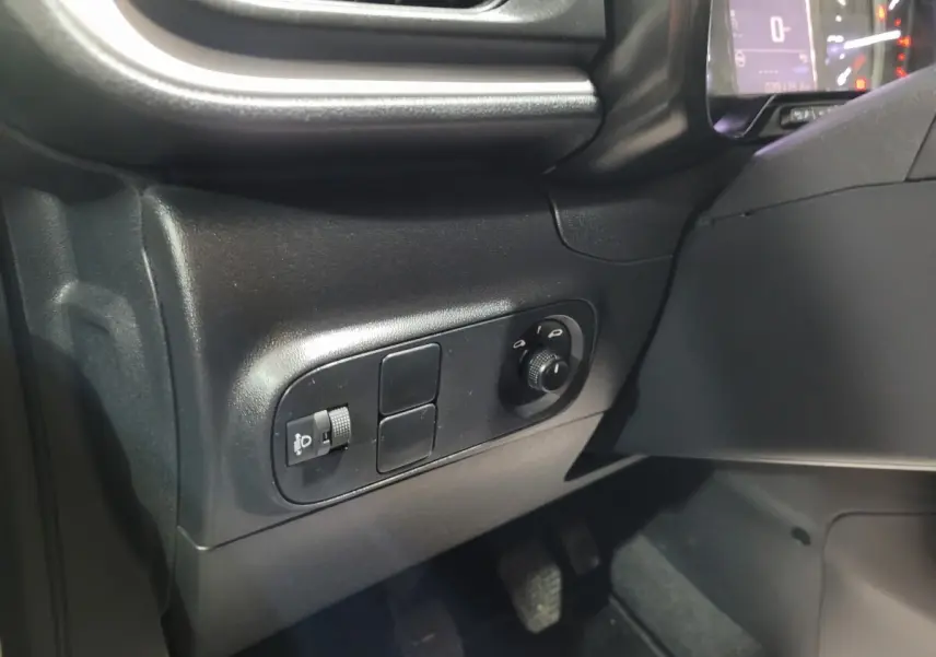 Gros plan sur les commandes d'éclairage et réglage des phares à gauche du tableau de bord de la Citroën C3 beige.