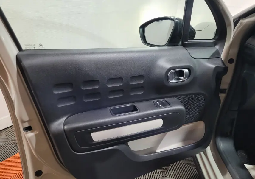 Vue intérieure de la porte avant gauche beige de la Citroën C3 2022 avec poignée argentée et commande de vitre.