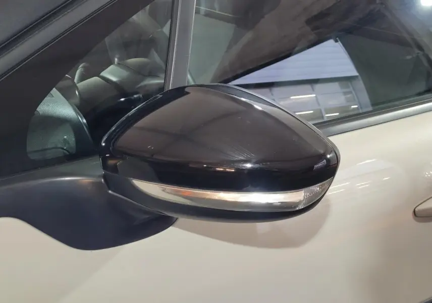 Rétroviseur extérieur noir en gros plan côté gauche d'une Citroën C3 beige 2022 avec clignotant intégré.