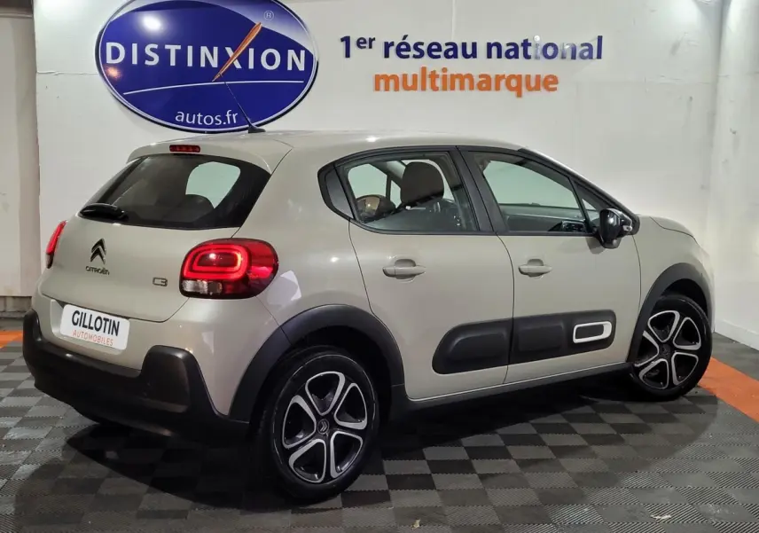 Vue 3/4 arrière droite d'une Citroën C3 beige 2022 avec protections latérales noires et jantes stylisées.