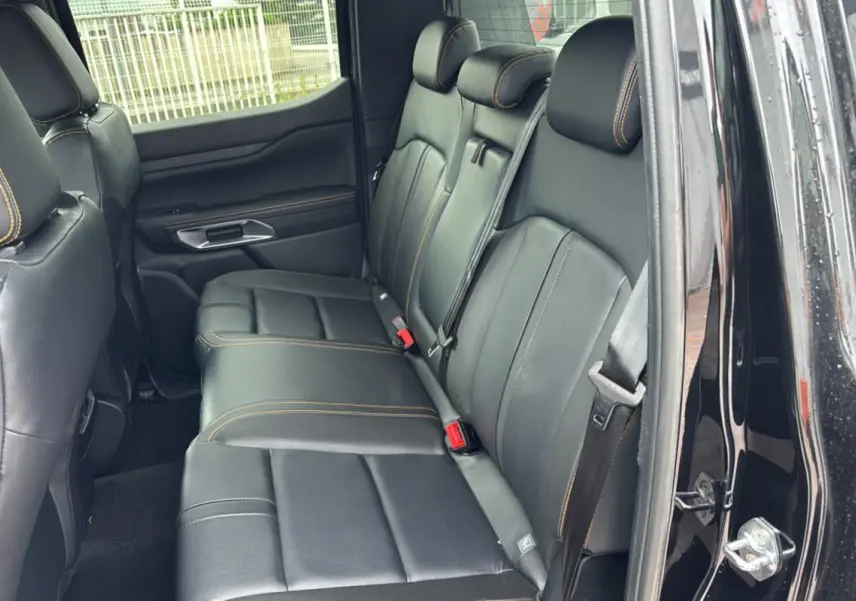Vue intérieure côté droit montrant la banquette arrière en cuir noir avec surpiqûres orange du Ford Ranger Wildtrak Plus 2025.
