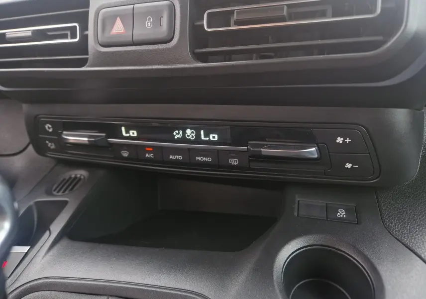 Vue rapprochée du tableau de bord du Peugeot Rifter gris platinium 2019, mettant en valeur la commande de climatisation digitale.