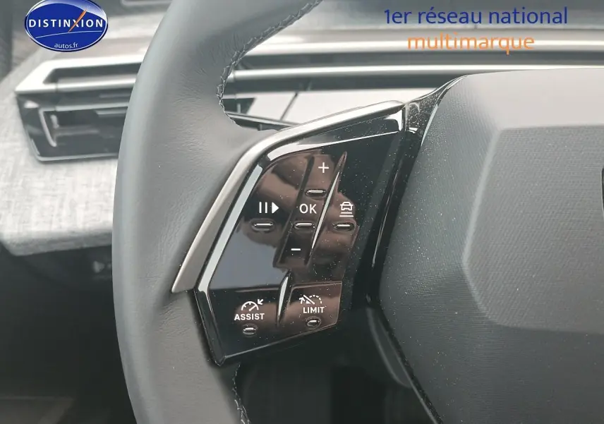 Gros plan sur les commandes gauche du volant cuir du Peugeot 5008 Hybrid 145 allure gris Artense, intérieur moderne.