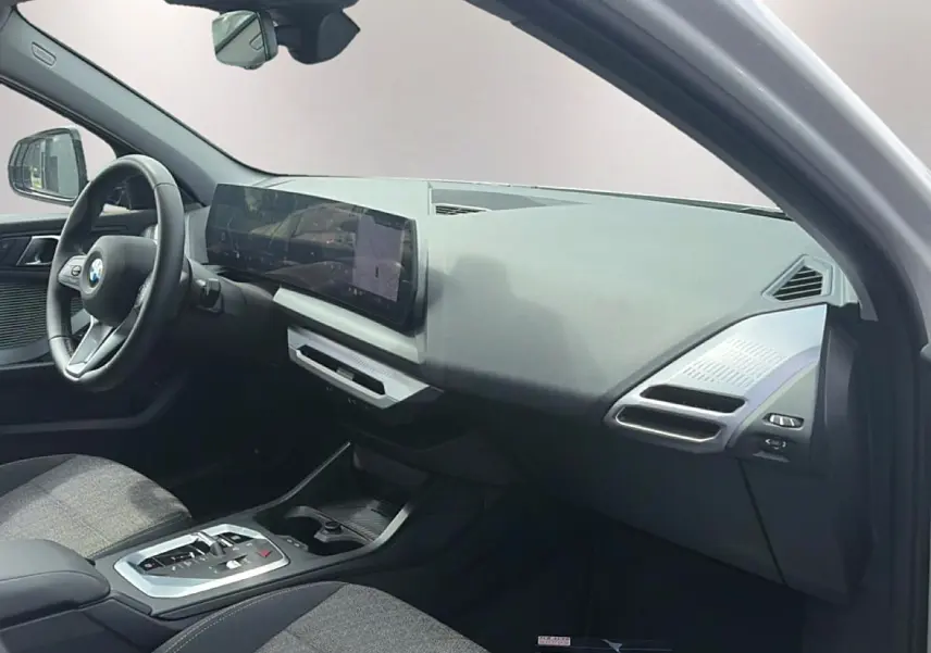 Vue intérieure côté passager de la BMW Série 1 120da 2025, tableau de bord moderne avec écran large et volant cuir M.