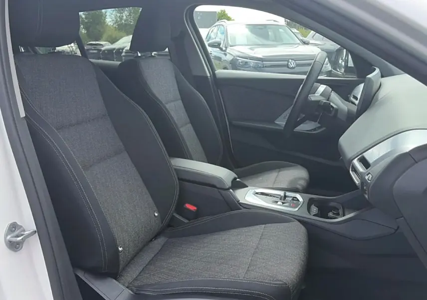 Vue intérieure côté conducteur de la BMW Série 1 blanche, sièges sport gris et console centrale avec boîte auto.