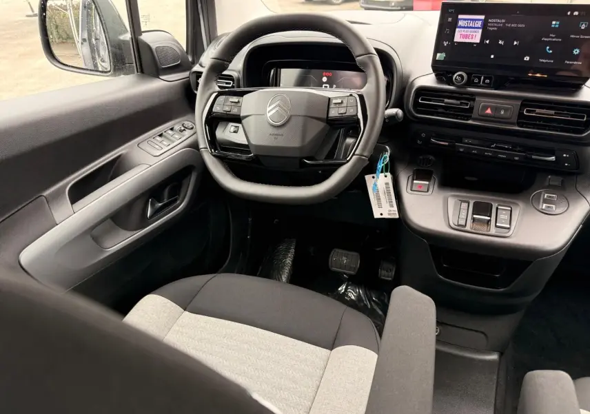 Vue intérieure côté conducteur du Citroën Berlingo gris Artense 2025, avec volant multifonctions et écran tactile central.