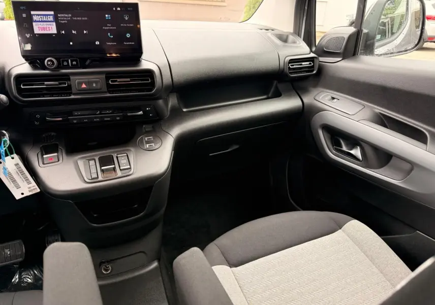 Vue intérieure côté passager du Citroën Berlingo 2025 gris, montrant la planche de bord et la console centrale moderne.