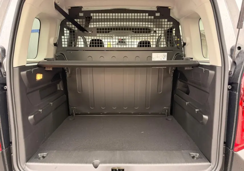Vue arrière du coffre spacieux du Citroën Berlingo gris, avec séparation métallique et tablette de rangement.