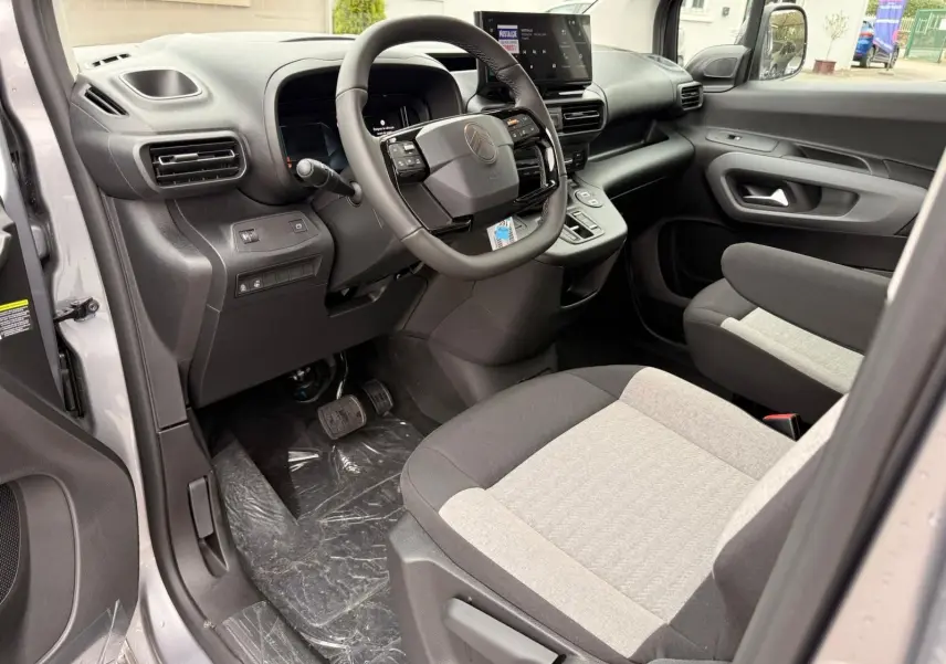 Vue intérieure côté conducteur du Citroën Berlingo gris Artense 2025, avec tableau de bord moderne et sièges bicolores.