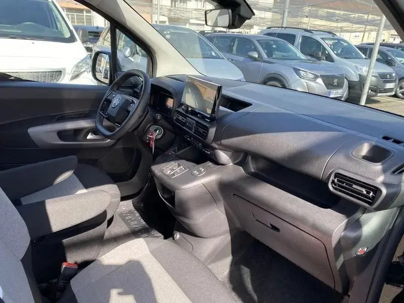 Vue intérieure côté conducteur du Citroën Berlingo gris Artense 2025, sièges tissu bicolore avec accoudoir central.