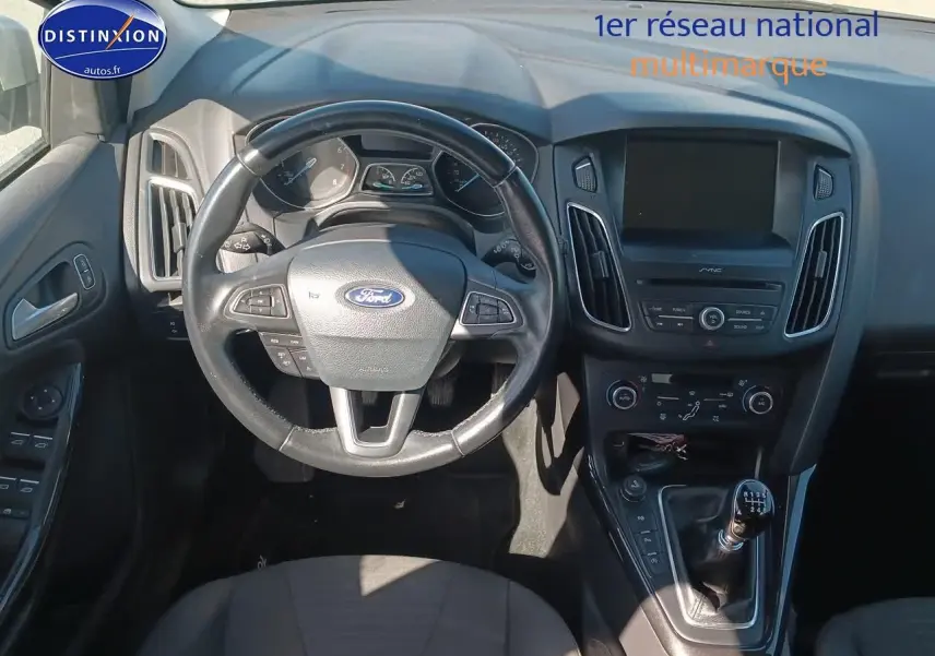 Vue intérieure centrée sur le volant cuir multifonction et la console centrale d'une Ford Focus gris clair 2017.