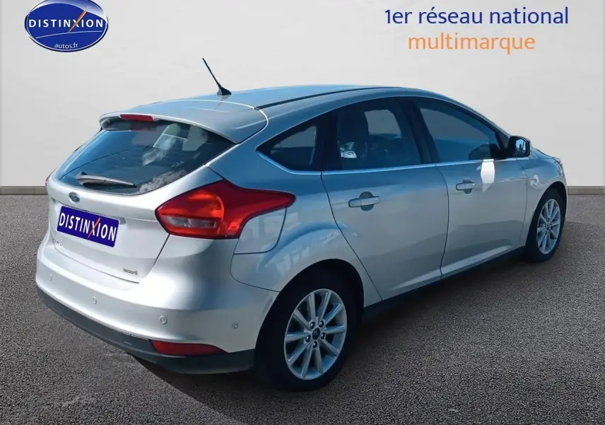 Ford Focus gris clair vue 3/4 arrière droit avec becquet et jantes alliage sur fond neutre