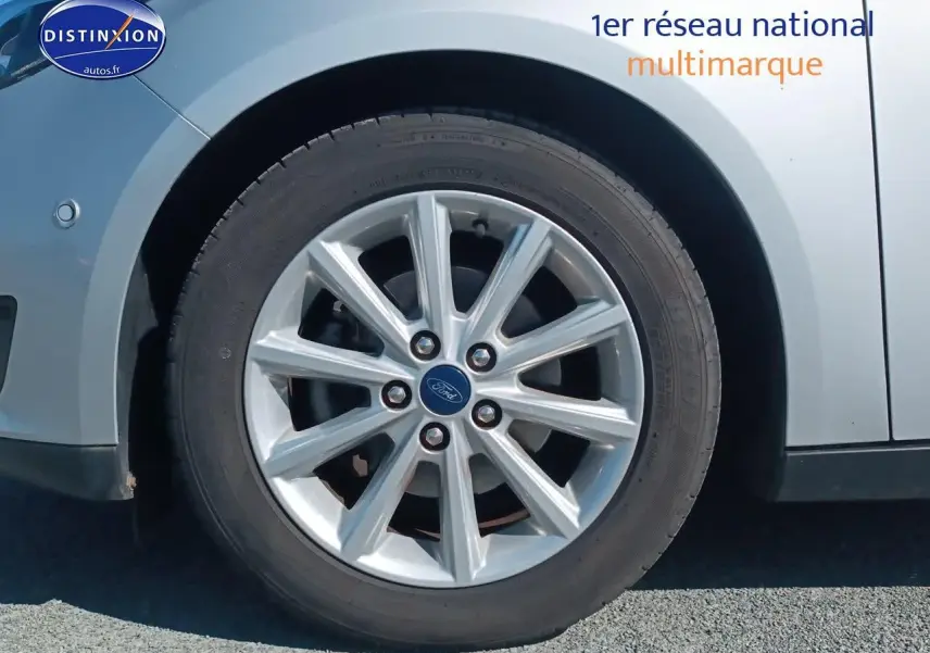 Gros plan sur la roue avant gauche en jante alu d'une Ford Focus gris clair 2017 finition Titanium.