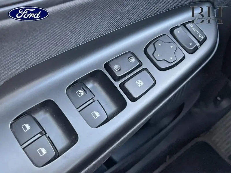 Panneau de commandes des vitres et rétroviseurs côté conducteur en plastique noir, intérieur d'une Ford.