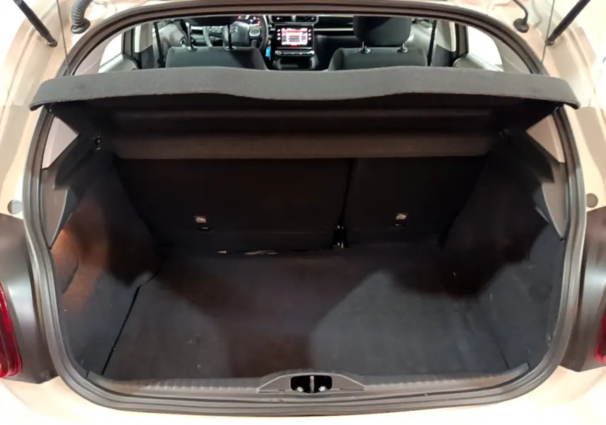 Coffre ouvert vu de l'arrière d'une Citroën C3 beige 2022, avec intérieur noir et tablette cache-bagages.