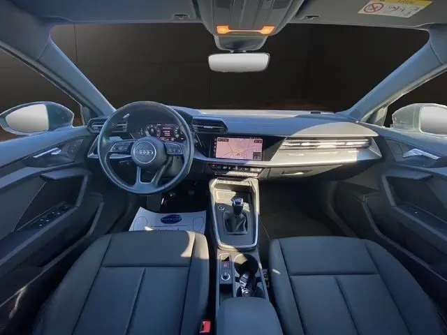 Vue intérieure avant de l'Audi A3 30 TDI 116 Business Line 2021 gris foncé, tableau de bord avec écran tactile et volant cuir.