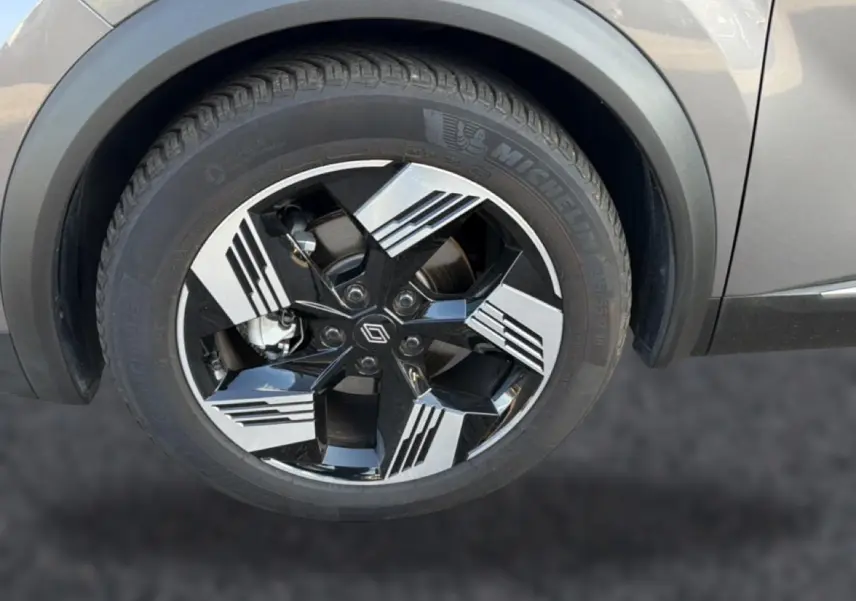 Gros plan sur la roue avant droite d’une Renault Symbioz gris cassiopée avec jante noire et argent au design moderne.