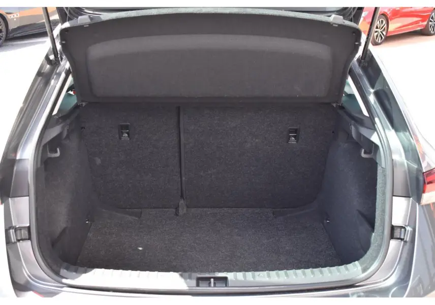 Coffre ouvert vu de l'arrière d'une Skoda Scala 2025 Graphite Grey Metallic, intérieur spacieux et tapis gris foncé.