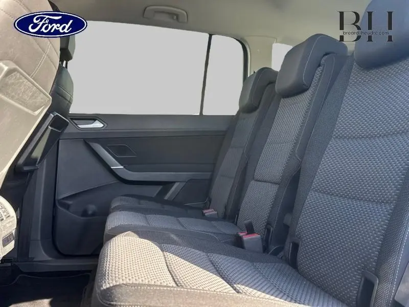 Vue latérale des sièges arrière en tissu noir du Volkswagen Touran 2023, mettant en valeur la troisième rangée et les appuie-têtes.