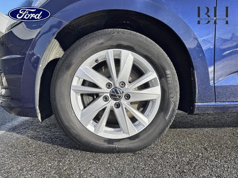 Gros plan sur la roue avant droite d’un Volkswagen Touran bleu Atlantique métallisé avec jante alliage.