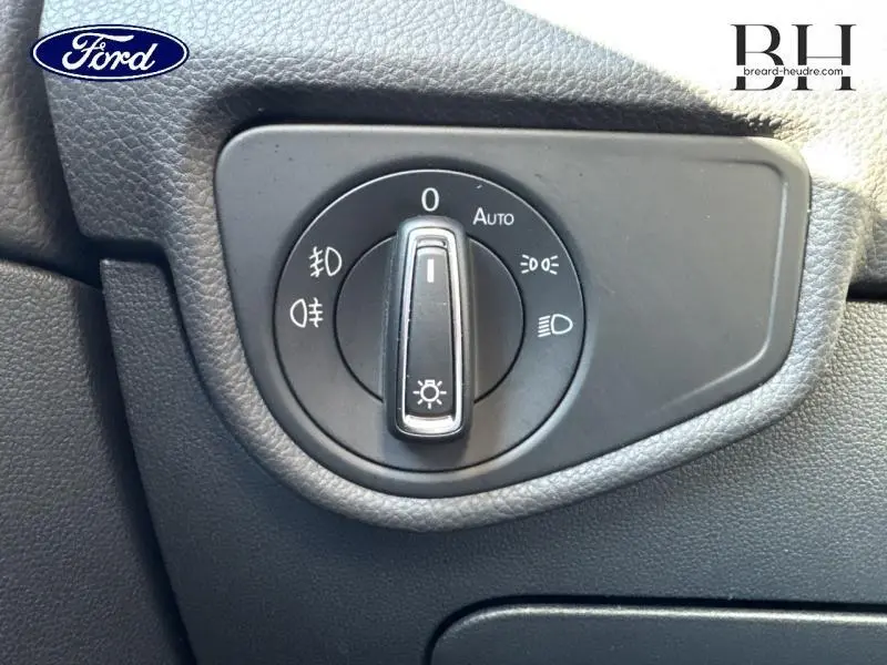 Gros plan sur la molette de commande des phares noire dans l'habitacle du Volkswagen Touran bleu Atlantique 2023.