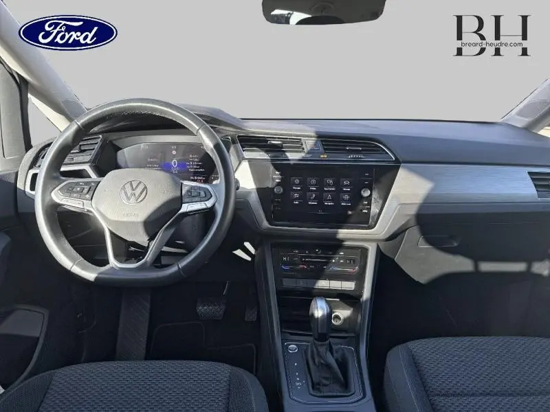 Intérieur avant du Volkswagen Touran 2.0 TDI 2023, vue du tableau de bord avec volant multifonction et écran tactile central.