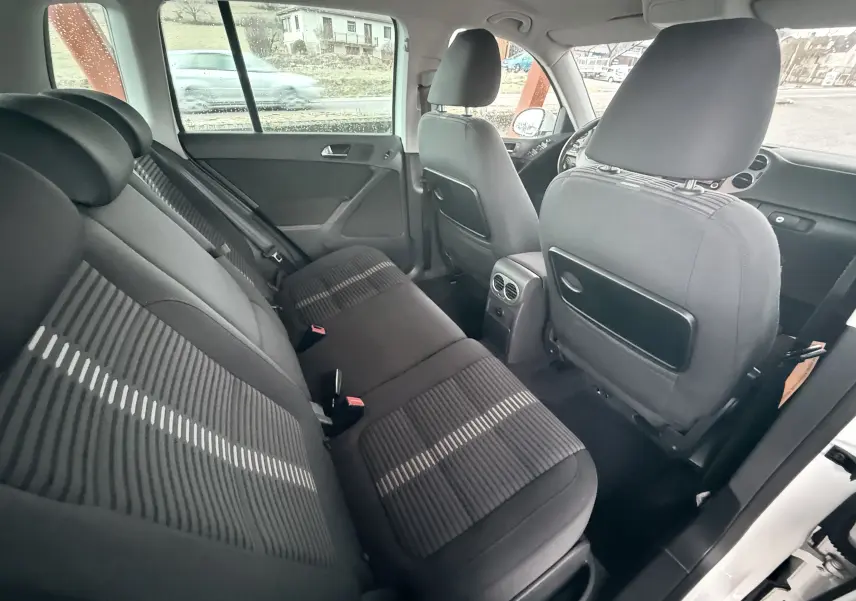 Vue intérieure arrière côté gauche du Volkswagen Tiguan 2.0 TDI 140 de 2010 avec sièges tissu noir et détails rayés.