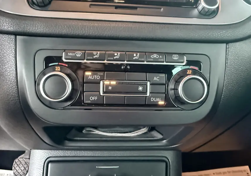 Gros plan sur la commande de climatisation automatique du Volkswagen Tiguan blanc, avec réglages à 22 degrés visibles.