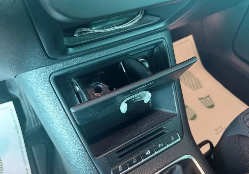 Vue rapprochée de la console centrale noire du Volkswagen Tiguan blanc, avec cendrier ouvert et commandes visibles.
