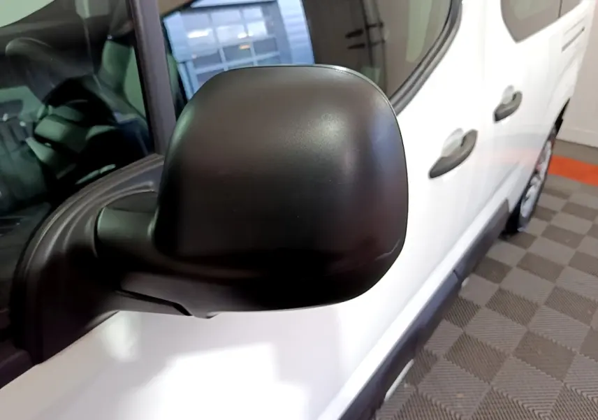 Rétroviseur noir en gros plan côté gauche d’un Citroën Berlingo blanc XL, vue partielle avant droite.