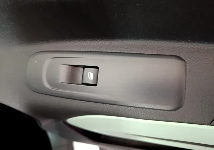 Gros plan sur l'interrupteur de lève-vitre électrique noir dans l'habitacle d'une Citroën Berlingo XL blanc.