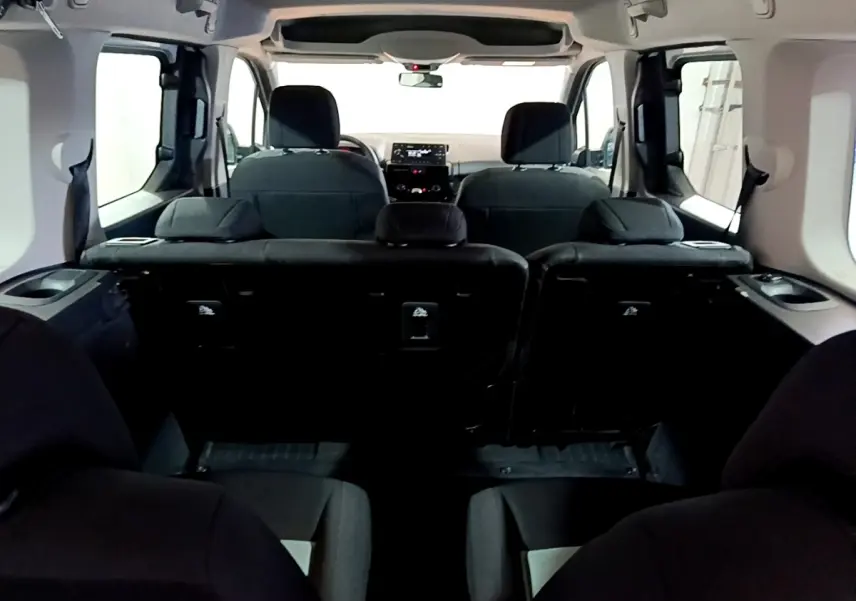 Vue intérieure arrière du Citroën Berlingo XL blanc, montrant les sièges arrière et le tableau de bord à l'avant.