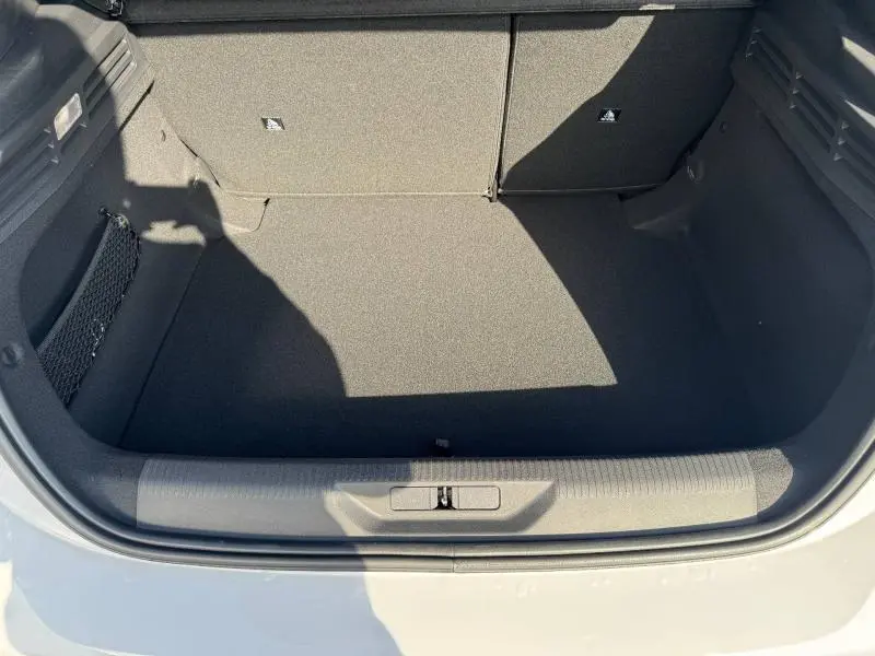 Vue plongeante sur le coffre ouvert d'une Peugeot 308 blanc Okénite, montrant l'espace de rangement vide et les finitions intérieures noires.
