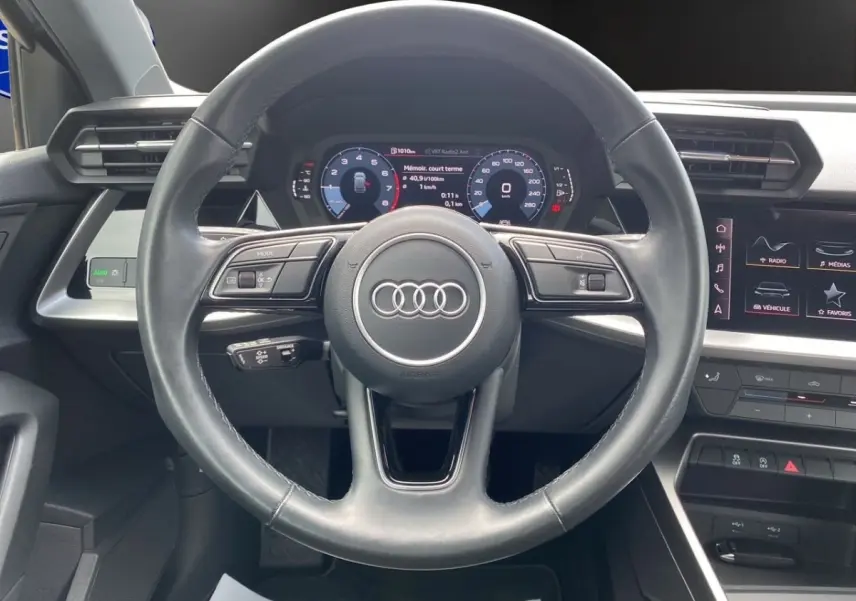 Vue centrée sur le volant cuir noir de l'Audi A3 30 TFSI 110 S Line 2021 avec tableau de bord digital et écran tactile.