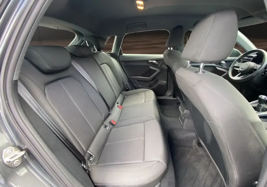 Vue intérieure côté gauche montrant la banquette arrière et les sièges avant gris foncé de l'Audi A3 30 TFSI S Line 2021.