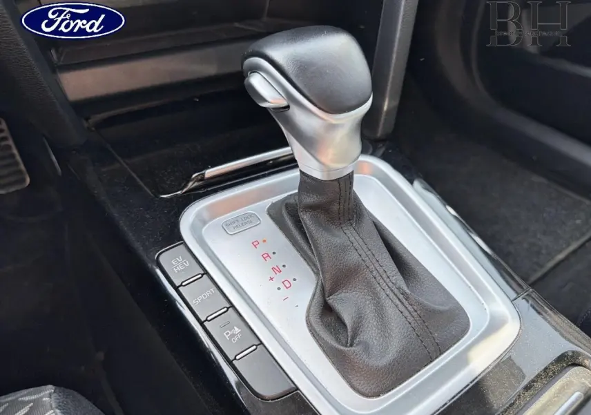 Levier de vitesse automatique en cuir noir avec console argentée, vue rapprochée de l'intérieur d'une KIA Xceed noire.