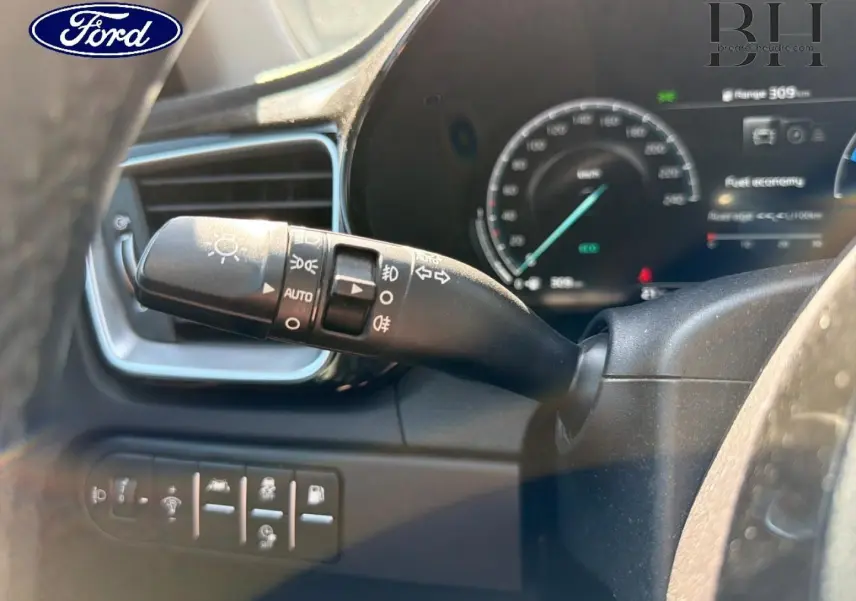 Gros plan sur la manette de commandes d’éclairage et clignotants côté gauche du volant d’une KIA Xceed noire.