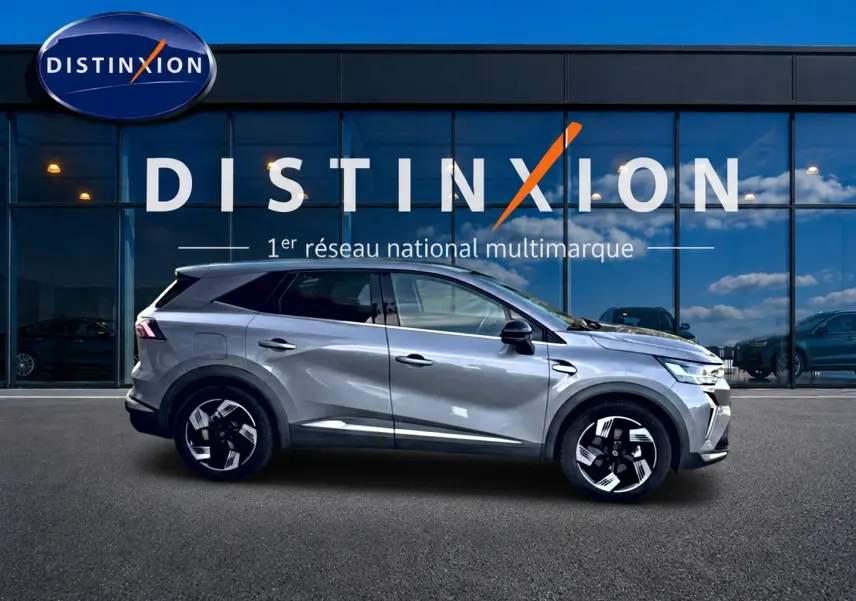 Profil droit de la Renault Symbioz gris 2025, SUV hybride avec jantes noires et toit surélevé devant vitrine Distinxion.