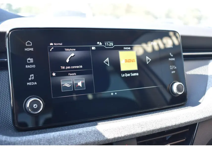 Écran tactile central de la Skoda Scala blanc glacier, affichant les options téléphone et radio FM/DAB.