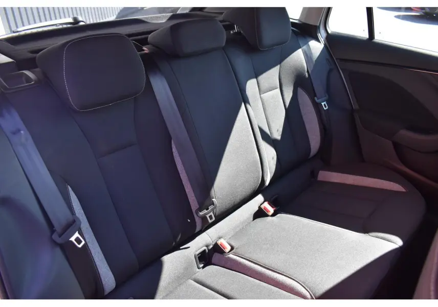 Vue latérale de la banquette arrière noire avec inserts gris et ceintures visibles dans une Skoda Scala blanche.