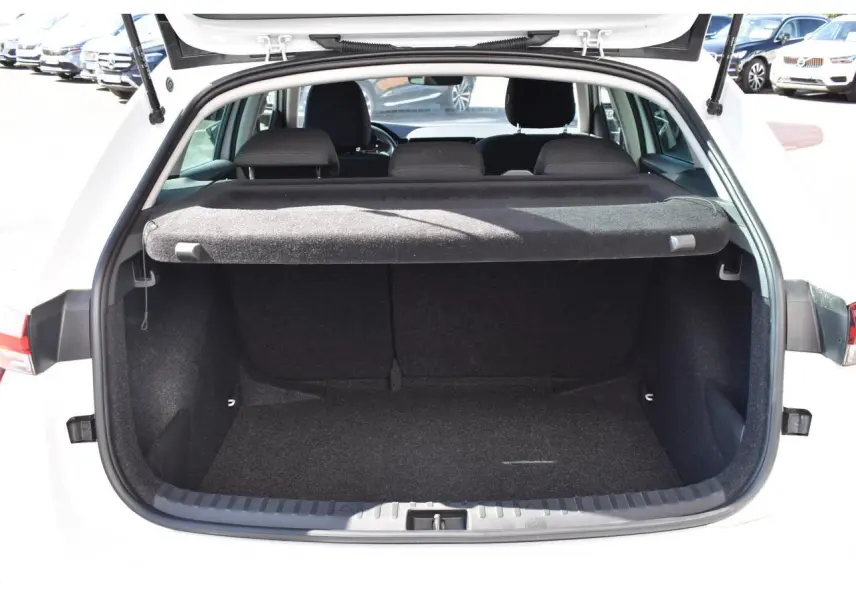 Coffre ouvert vu de l'arrière d'une Skoda Scala blanc glacier, avec cache-bagages et banquette arrière noire visible.