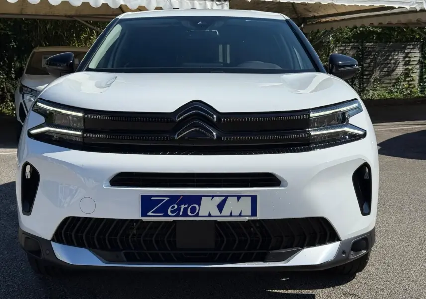 Vue de face d'un Citroën C5 Aircross blanc banquise 2024 avec calandre noire et plaque Zéro KM visible.